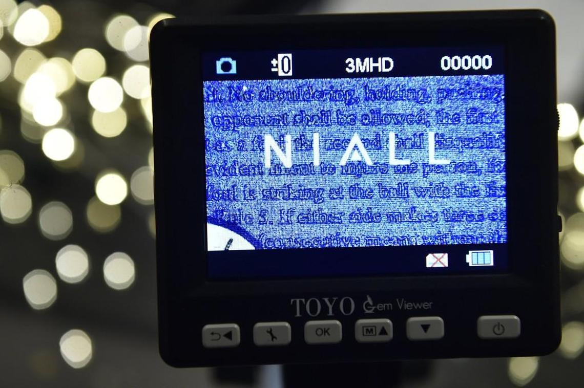 Niall on the Plaza sells a watch with the 13 rules of basketball microinscribed on the watch face. The tiny words are seen magnified through a device.