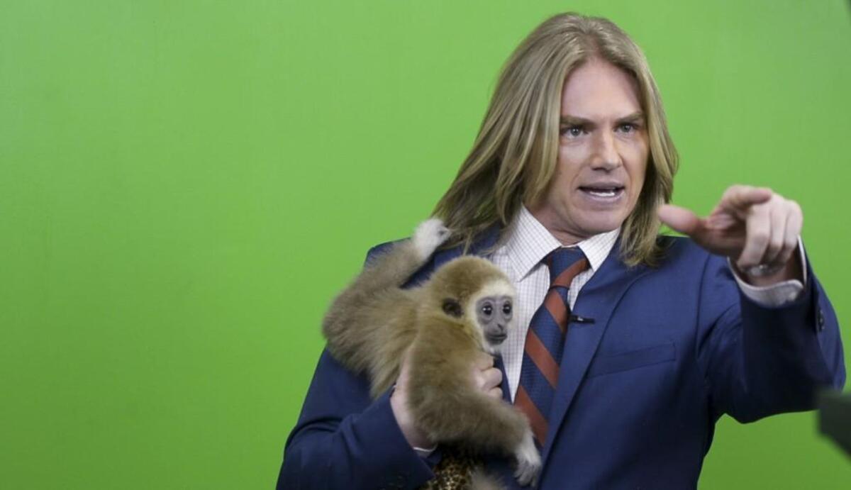 FILE PHOTO: Tristen Woods holds a rescued white-cheeked gibbon while shooting a commercial for his firm, Jungle Law Group, in 2018. Woods, a former model and actor, has become locally famous for his intentionally cheesy billboards and commercials.
