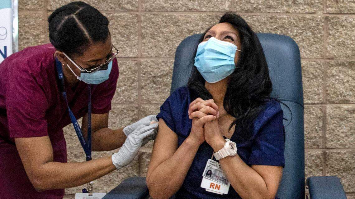 Nurse Maritza Beniquez, seated, reacts after receiving the Pfizer-BioNTech COVID-19 vaccine, at University Hospital, in Newark, NJ, Tuesday Dec. 15, 2020. Beniquez was the first person in New Jersey to receive the vaccination.