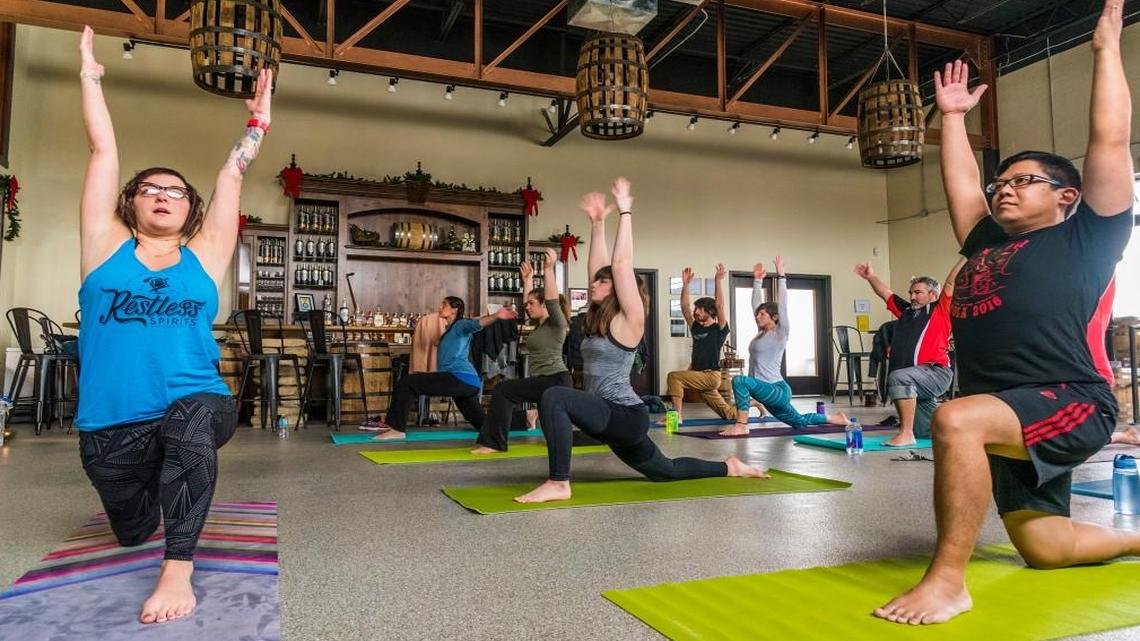 Heather Rama (left) leads a yoga class designed for service industry workers at a distillery every month. December’s gathering was at Restless Spirits Distilling in North Kansas City, where attendees included husband Ryan Rama (right). She also teaches similar classes weekly at Hagoyah in Waldo.