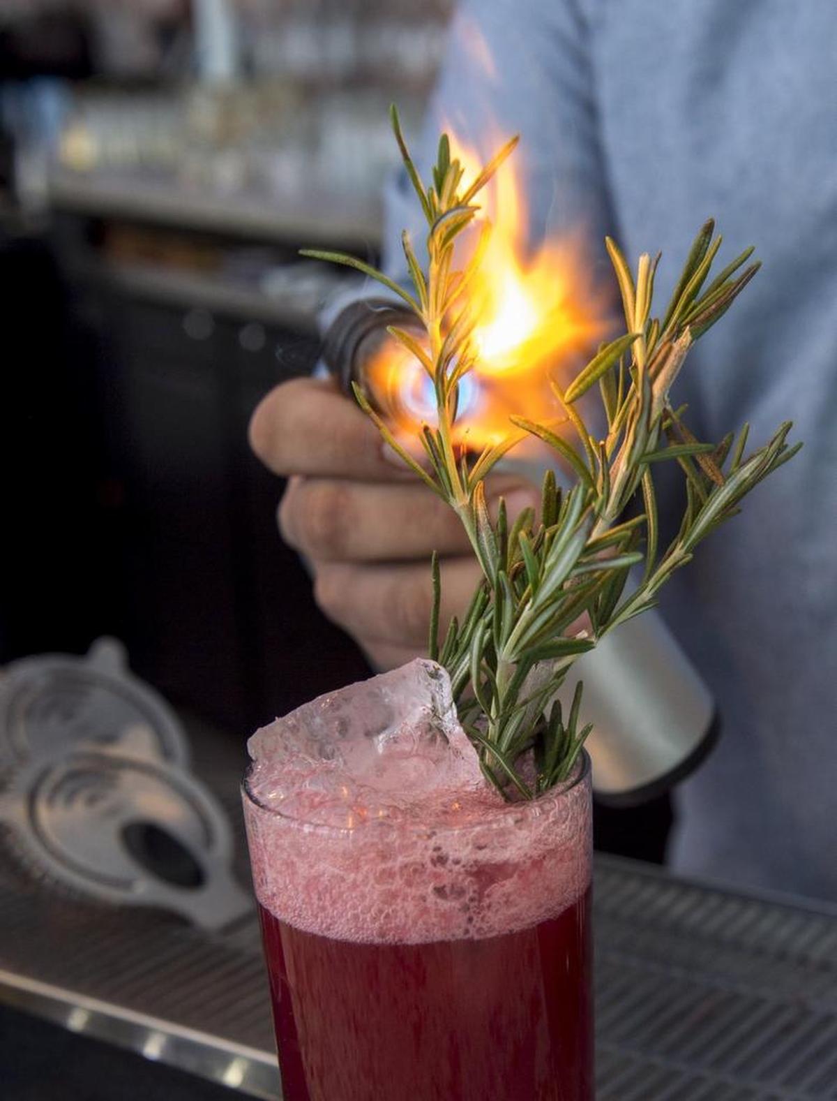 From 2016: Erik Mariscal, general manager and bartender at SoT, uses a kitchen torch to flame a substantial rosemary garnish.