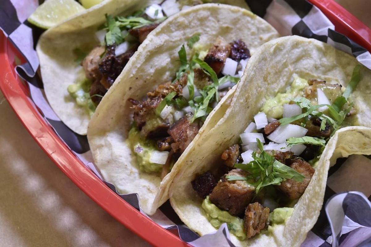 Smoked Carnitas BBQ Taco: crispy smoked pork shoulder, guacamole, salsa verde, fresh onion, cilantro.