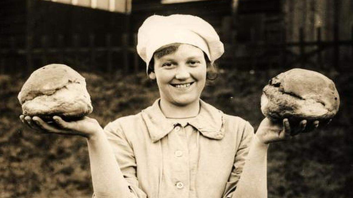 


A Women’s Army Auxiliary Corps (W.A.A.C.) member proudly displays two fresh loaves of bread baked for British troops. Top photo: Army men recently from the trenches hold food tins and line up for French wine.
