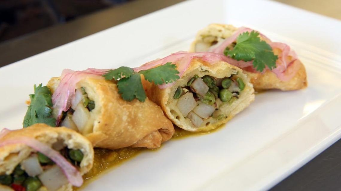 Vegetable samosas served with cilantro, pickled onions and carrot chutney.