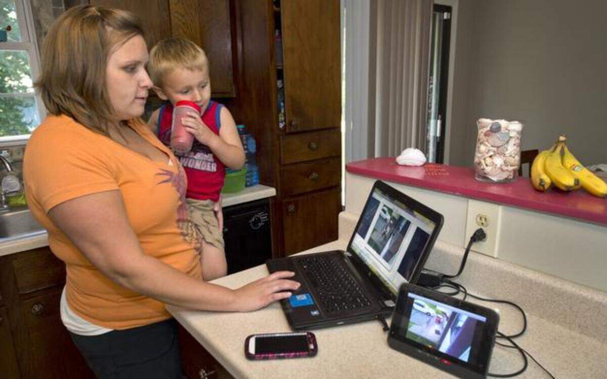 
Emily Estrada of Grain Valley, with son, Charlie, 3, monitors her home security system through a laptop. She can also monitor it through a tablet or smartphone. 
