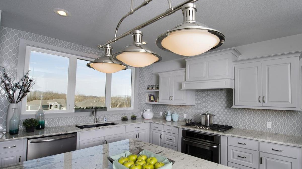 The kitchen in Don Julian Builders’ Glendale II model home has “Fixer Upper” style features, such as big windows to let in natural light, light-colored cabinets, a big island and industrial-style lighting.