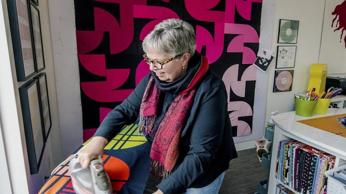 Jacquelyn Gering creates her quilts in a tidy studio in her Westside home. Here she works on a quilt called “Honey’s Moon.” The quilt in the background was also a work in progress.