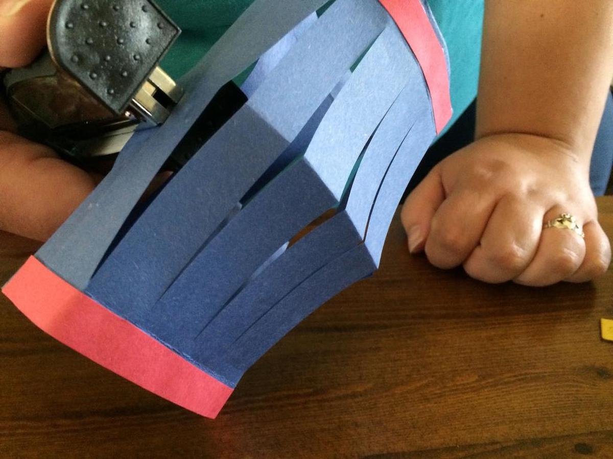 Open the construction paper, pull out all the slits to resemble lantern shape and staple the two sides together.