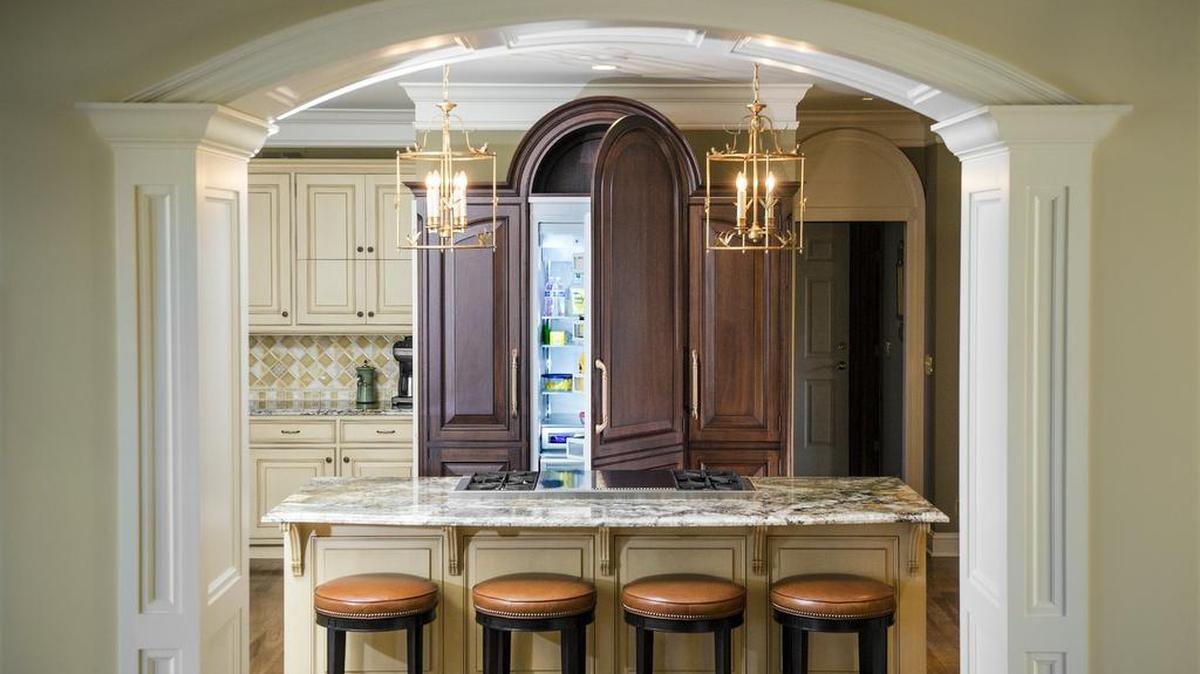 Eye-pleasing symmetry and impeccable finishes highlight a truly efficient kitchen, with a tight-functioning work triangle and personalized storage units customized to the client’s wares and appliances. The dominant feature of the room is actually a fridge and freezer with pantry storage on the side for daily use.