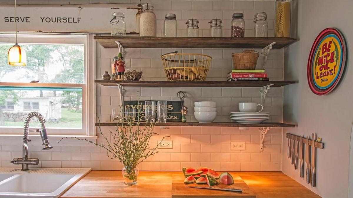 
Andrea Darr and Michael Gekas created kitchen shelves out of wood salvaged from their home renovation and Anthropologie brackets. The vintage metal sign above the farmhouse sink was discovered in a barn on their property near the Kansas Speedway.
