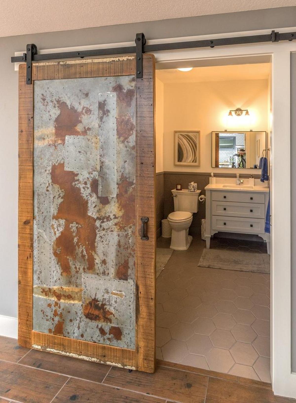 A main floor bathroom door is from found metal and wood remnants and finished with a rusty look;.