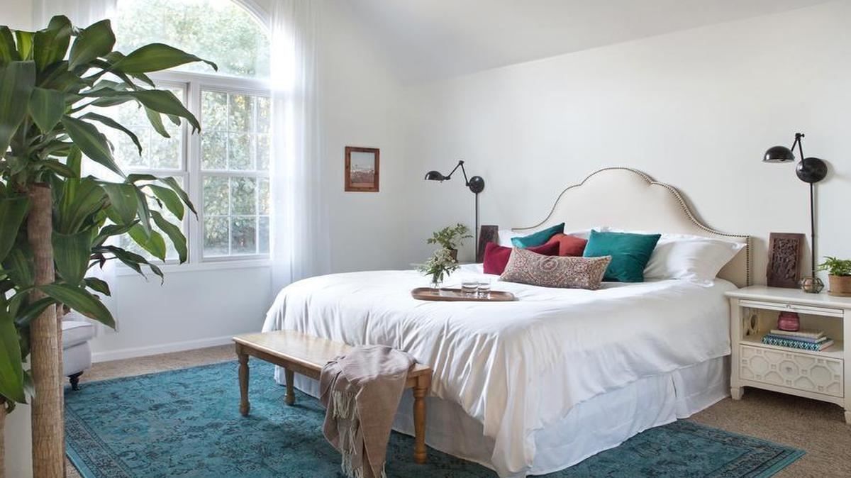 Julie Blanner painted the Bartlows’ bedroom walls white, then introduced pops of color with the rug and pillows.