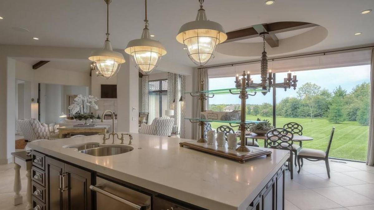 The glass wall fills the kitchen with natural light and offers a view of a green, rambling lawn.