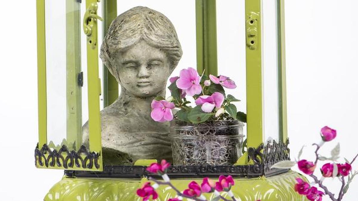 
We created this spring vignette using a green lantern ($79.99) and bust of a woman ($14.50) from Pryde’s. We added a small Mason jar filled with moss and fresh impatiens and a silk floral branch. It would be a perfect piece in a boudoir or on a buffet table during a girls’ luncheon.
