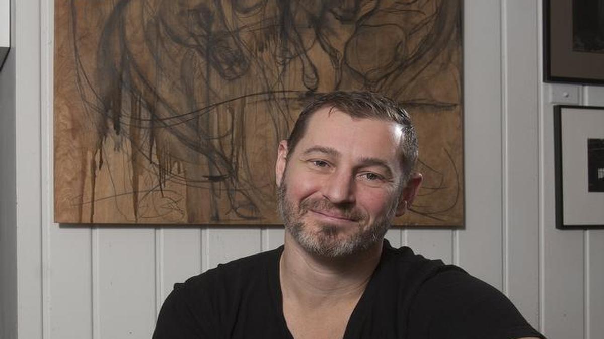 Kansas City Art Institute alum Caleb Bowman and his wife use their home as their gallery. Behind him is “Standing at the Gate.”