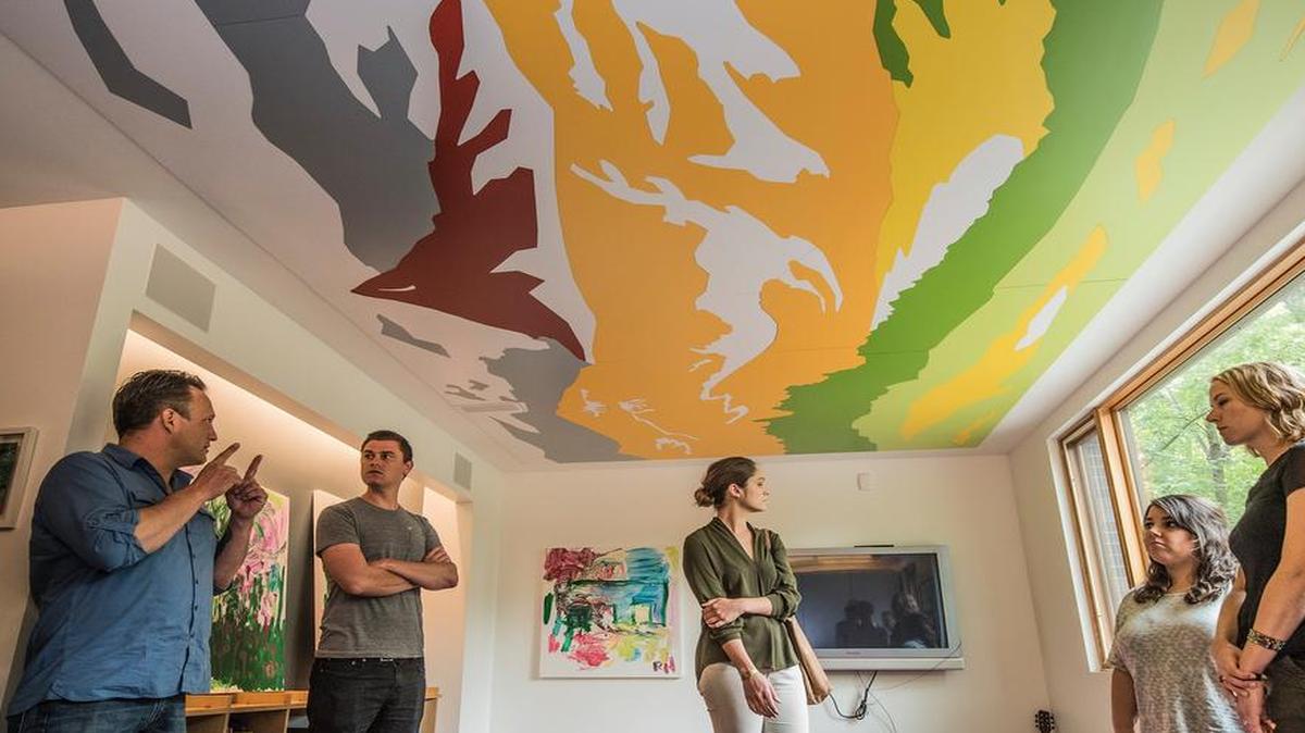 
Chris Rodriguez (far left) and Dan Brown take Hufft Projects employees on a tour of Jesse and Matthew Hufft’s Roanoke home. The mural on the ceiling, resembling a Thomas Hart Benton painting, was created by an intern using a 5,000 pound router.
