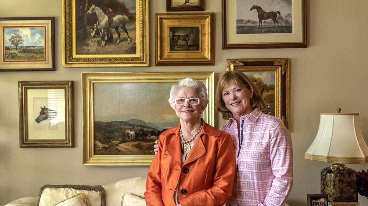 Mary Pogson, left and her daughter Mary Ellen Knop pose in front of a wall of Mary Pogsonâ€™s favorite horse horse portraits.