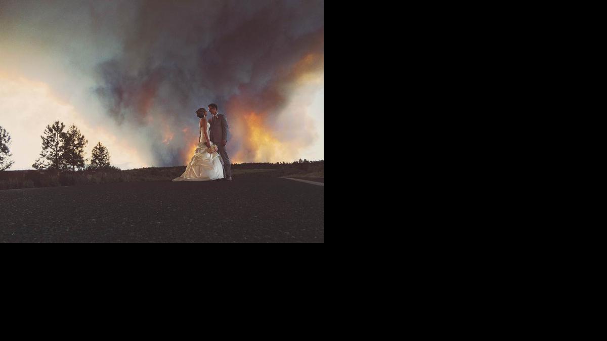 
Newlyweds Michael Wolber and April Hartley pose for a picture near Bend, Ore., as a wildfire burns in the background. Because of the approaching fire, the minister conducted an abbreviated ceremony and the wedding party was evacuated to a downtown Bend park for the reception.
