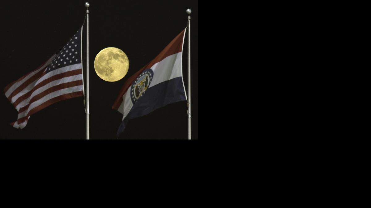 The American flag and Missouri state flag at Kauffman Stadium add foreground interest in this photograph of a supermoon in July 2014.