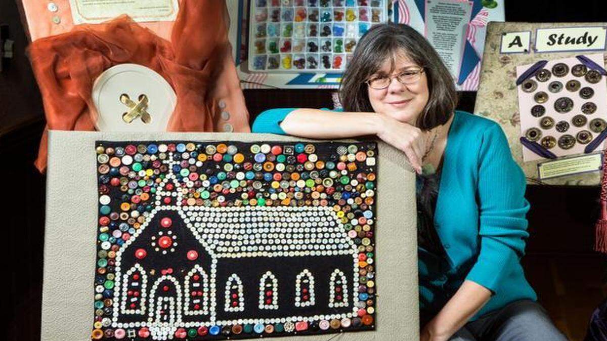 
Lise McIntyre is surrounded by some of the buttons in her Traveling Button Museum, including the first collection — the church design piece — she purchased more than 20 years ago.
