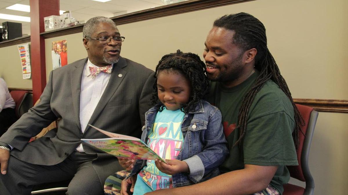 
Kansas City Mayor Sly James (left) and barbershop owner Joey Thomas helped Thomas’ 4-year-old daughter, Joye, read a book about Barbie. 



