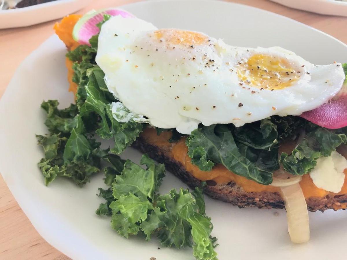 Breakfast veggie tartine features warm butternut squash puree layered with candied onion, Green Dirt Farms fresh cheese, kale and over-easy eggs on seasame bread, $8 available all day.