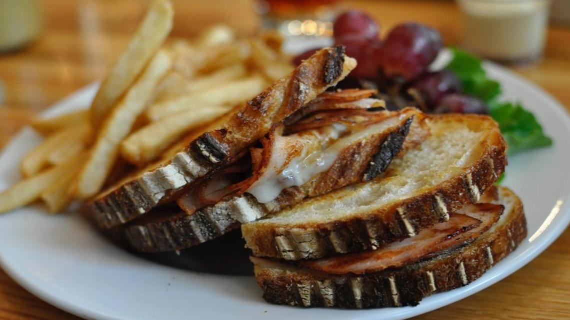 Free State’s menu features a smoked turkey sandwich on country French bread with a side of fries and a cluster of grapes.