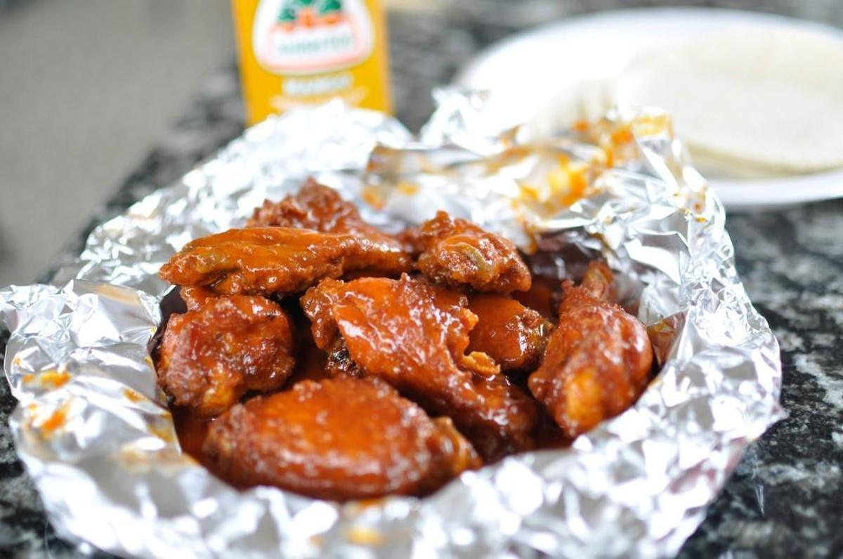 El Pollo Rey’s Buffalo wings are served saucy and sizzling-hot in a pocket of aluminum foil.