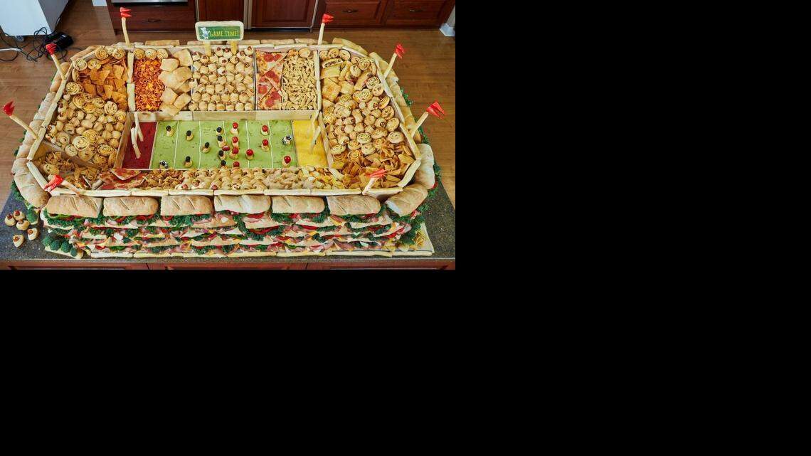 
This “snackadium,” features sub sandwiches, salsa, guacamole and cheese dip among pizza slices and other snacks. 
