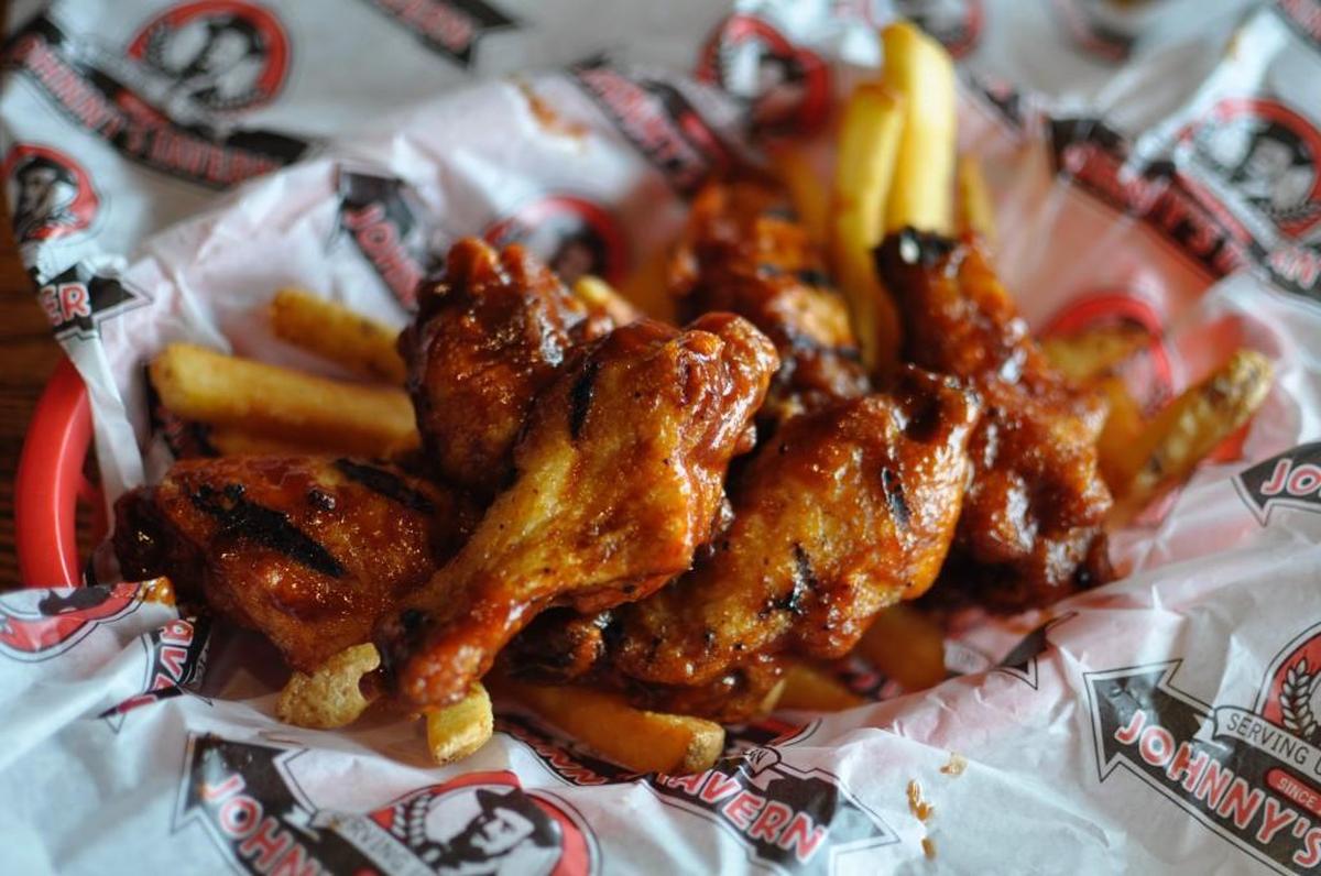Johnny’s Tavern makes its popular Wilson Wings by frying and grilling chicken wings, then coating them in hot sauce with a hint of sweet barbecue flavor.