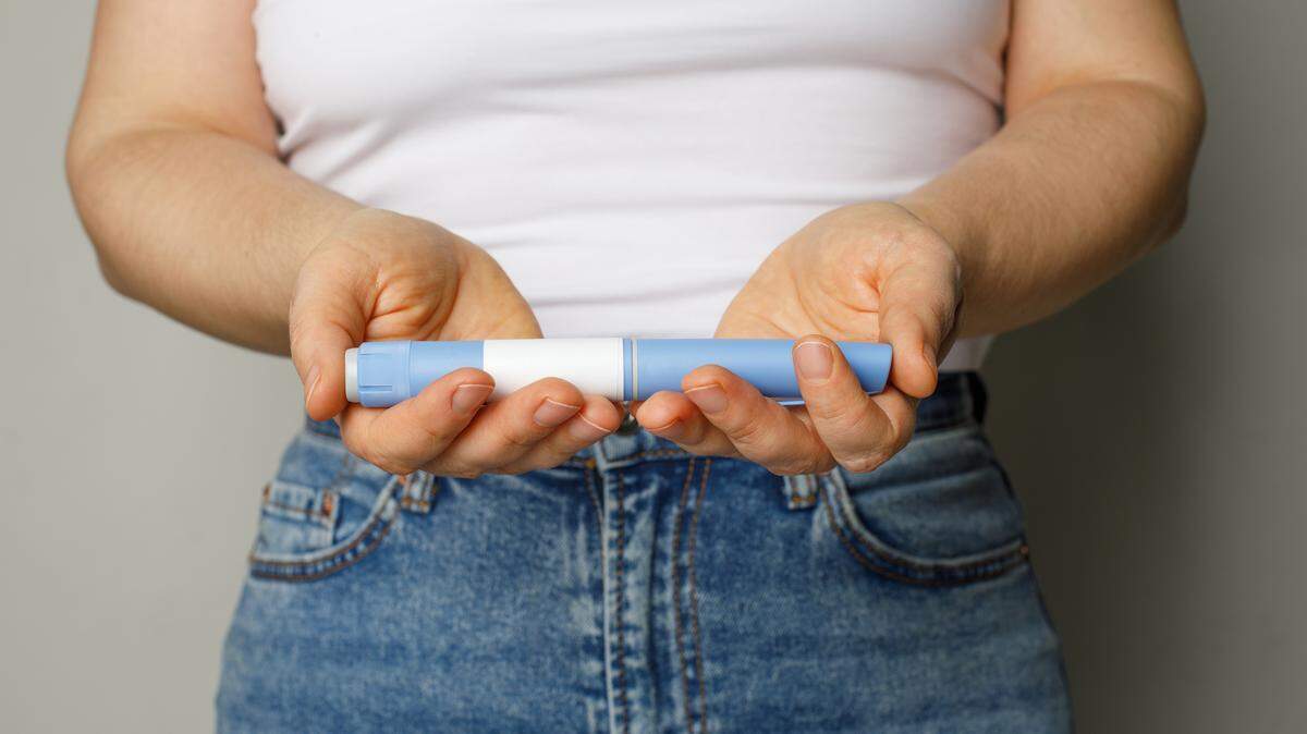 A woman holding up GLP-1 medication. 