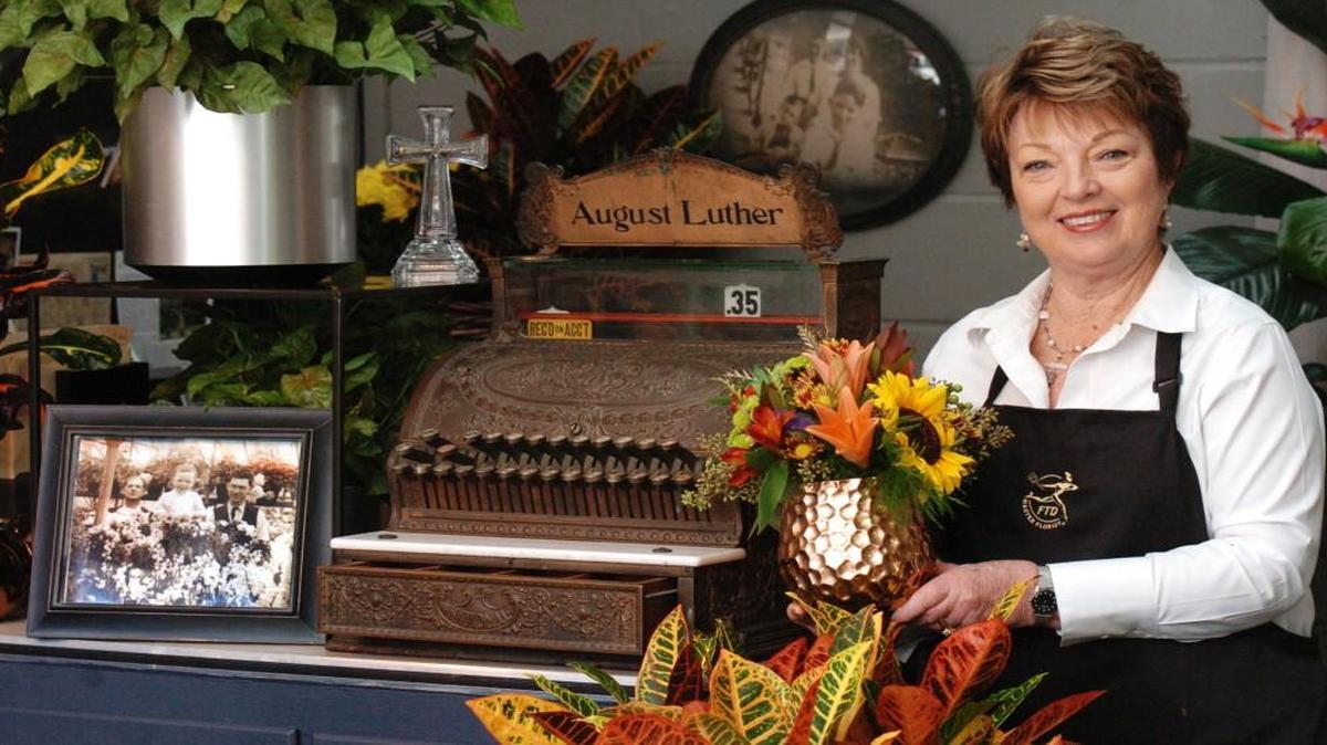 
Bonnie Luther-Hayes, the fourth-generation owner of Luther Florists & Greenhouses at 3220 E. 27th St., has kept some of the store’s original features, including a 100-year-old cash register. It bears the name shared by her great-grandfather and grandfather, August Luther. The photograph (circa 1916) to the left of the register shows her grandfather August F. Luther and father Orlando A. Luther with a store employee.
