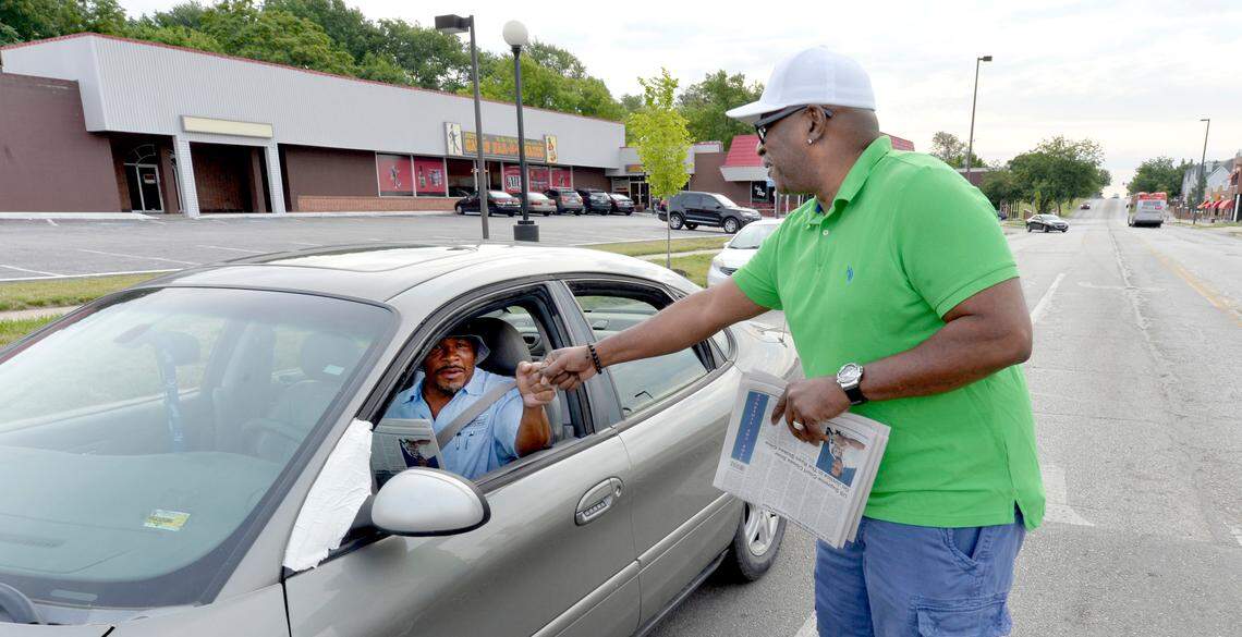 Eric Wesson, publisher of the new weekly newspaper The Next Page KC, fist bumps a driver while handing out free copies of his paper at 12th Street and Brooklyn Avenue.