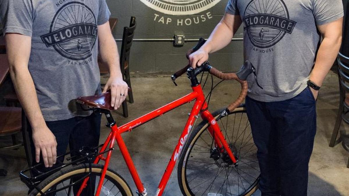 Steve Borden (left) and Kiley Sutter, co-owners of VeloGarage and Tap House, stand on Thursday next to a bike sold in their adjacent shop in North Kansas City.