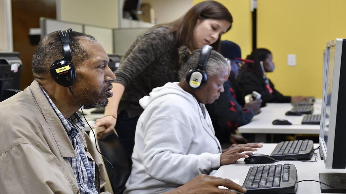 Students at Literacy Kansas City use software to improve their reading skills. Stewart Carter (left) worked on one of the computers Wednesday as instructor Sarah Bell helped Vonzille Fayne.