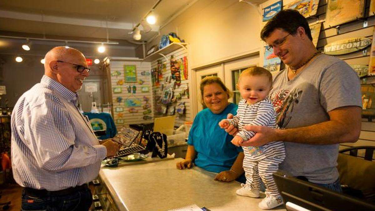 Ray Rosen of Independence (left) purchases an item with his wife, Kathy, for their newly renovated beached-theme bathroom from the owners of Barefoot Beach Bums, Mark and Lynn Gould, and their daughter, Makenzie, at the store at 5 Main St. in Parkville. The store offfers a wide variety beach-themed decor and clothing.