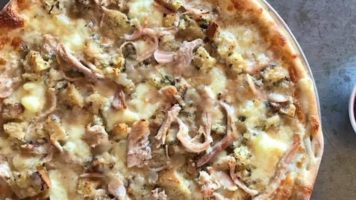 Turkey pizza with mashed potatoes, gravy and a side of cranberry sauce.