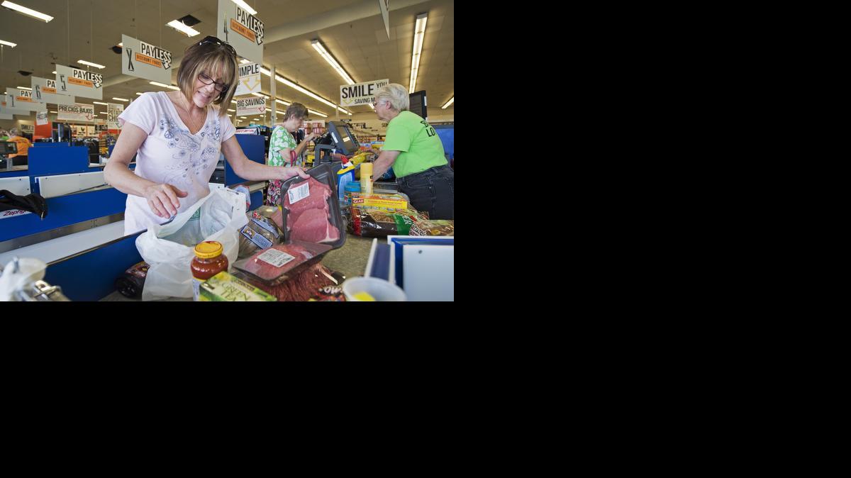 
Michele O’Neil of Overland Park (left) bagged her own groceries Monday, part of the cost-cutting moves at Payless Discount Foods. Cashier Gladys Sours rang up her purchases and then those of Pam Clair of Olathe. 
