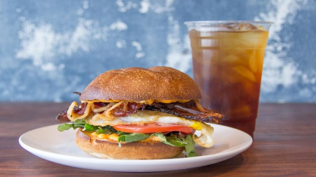 Sundry’s Barnyard Breakfast Sandwich with house-smoked bacon, egg, local greens, tomato and sriracha mayo on a Farm to Market egg bun.