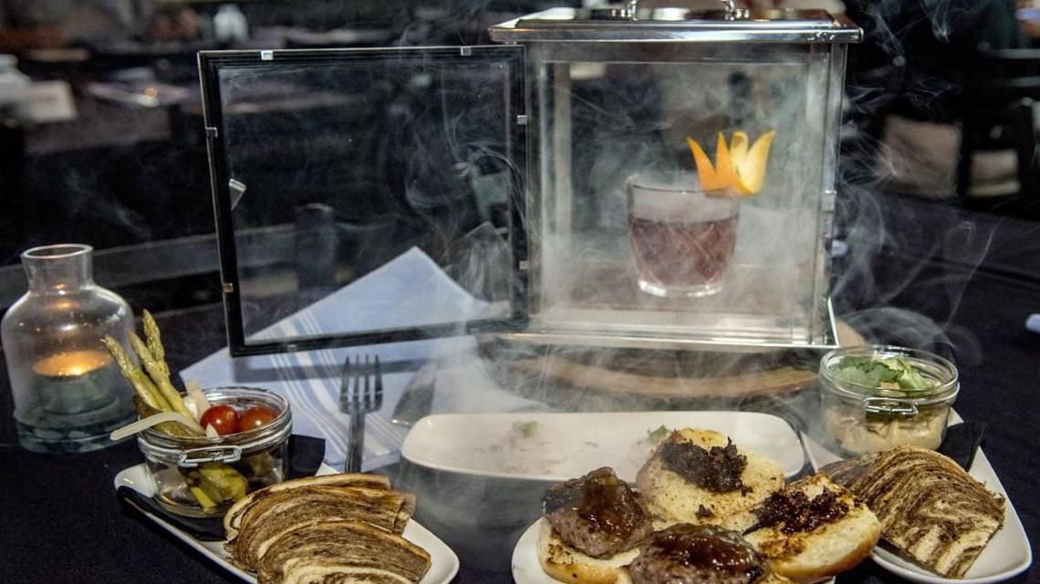 Offerings at Repeal 18th Bar & Bistro include the Smoking Hog cocktail and small plates (from left) pot o’ pickles, scallop ceviche, steakburger sliders and chips and dip.