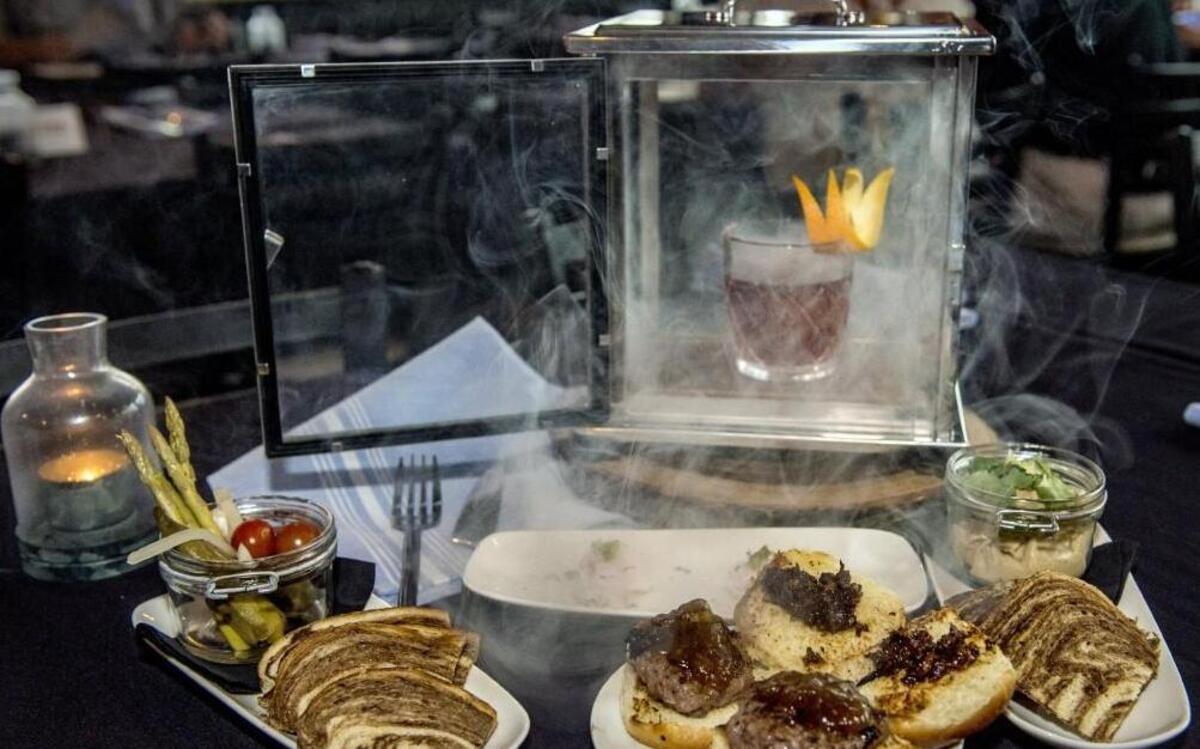 Offerings at Repeal 18th Bar & Bistro include the Smoking Hog cocktail and small plates (from left) pot o’ pickles, scallop ceviche, steakburger sliders and chips and dip.