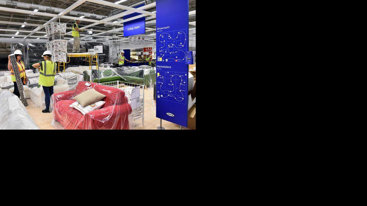 A sneak peek inside the Ikea store in Merriam on Tuesday found visual merchandisers Carrie Koslow (left) from the Pittsburgh store and Wiebke Crum from the Tampa store consulting in the sofa area of the living room section as subcontractor Thomas Creach hung lights.