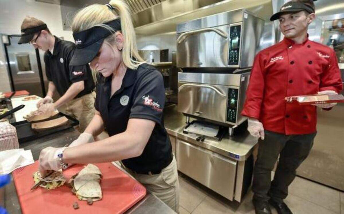
Chef Nick Powell (right) watched Brie McKinney and Brent Oberly make flatbread sandwiches last Wednesday ,at the Quik Trip at 4005 Little Blue Parkway in Independence. The convenience store chain has added kitchens to many of its stores, serving toasted sandwiches, breakfast items, smoothies and made-to-order pizzas.
