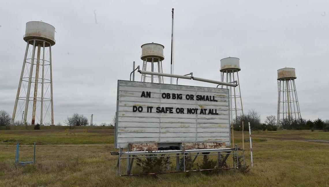The remains of a safety sign stand under water towers at the old Sunflower Army Ammunition Plant near De Soto. A new timeline pushes back redevelopment of the land to 2028.