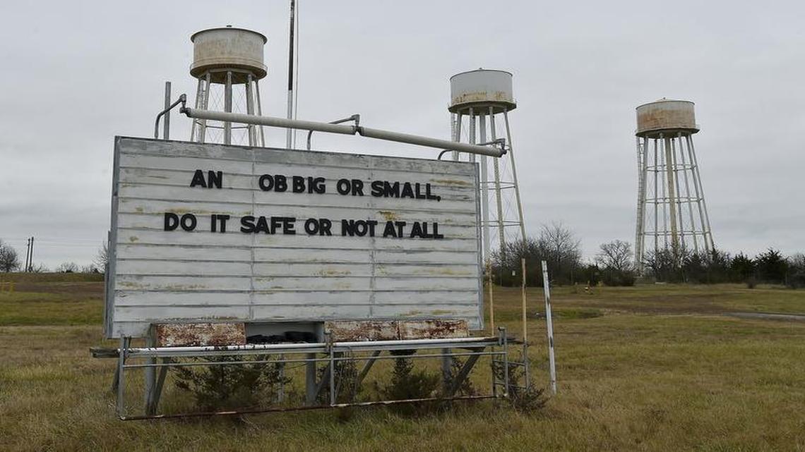 The remains of a safety sign stand under water towers at the old Sunflower Army Ammunition Plant near De Soto. A new timeline pushes back redevelopment of the land to 2028.
