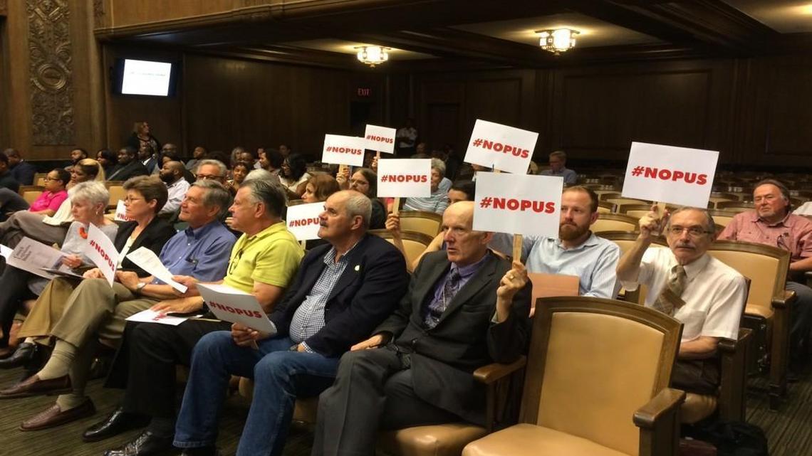 Opponents of the proposed Opus apartment project at Westport Road and Broadway held signs against the project Thursday afternoon at the Kansas City Council meeting.
