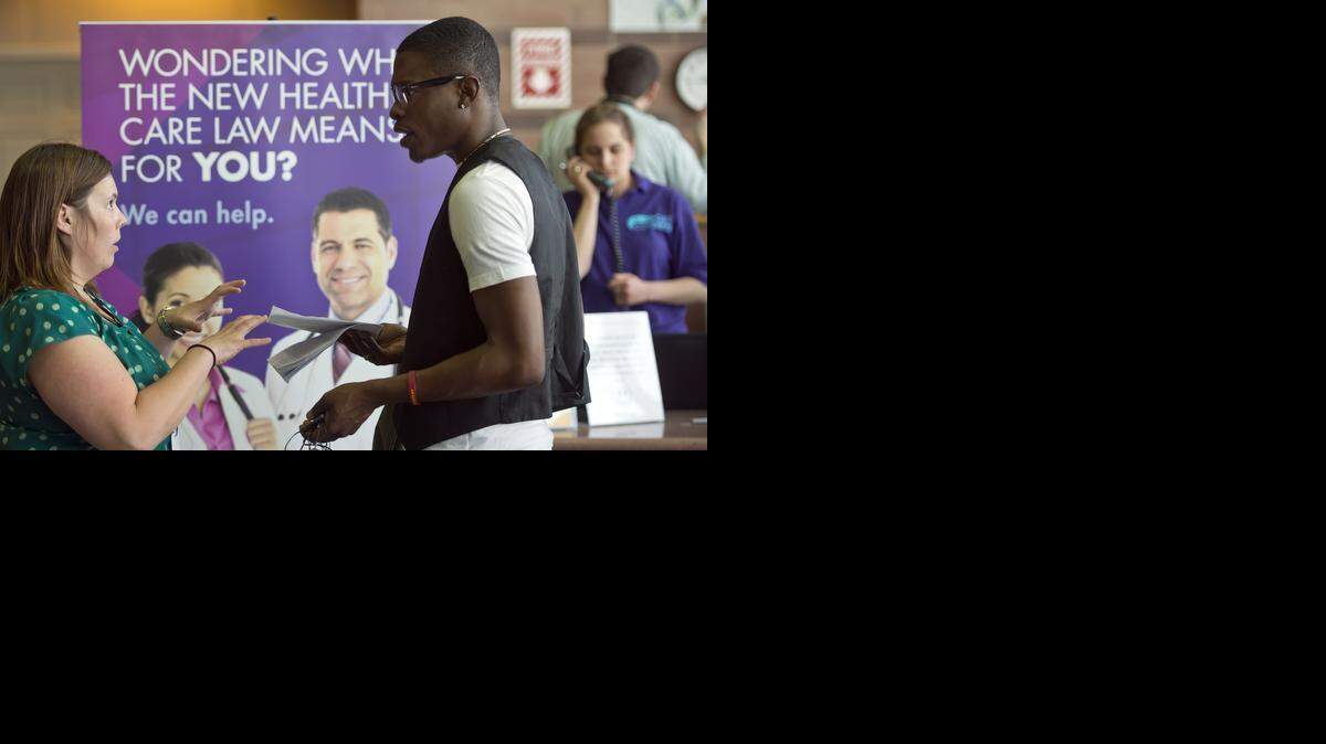Jessica Peters (left), who works at Swope Health Services, answered questions posed by Reginald Smith (center) of Kansas City about his application for health insurance under the Affordable Care Act.