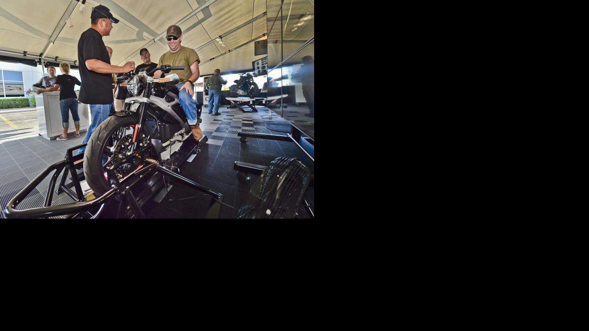 
Rich Guieb (left) assists Brad Lowrance as he simulates riding an electric motorcycle on at Worth Harley-Davidson in Kansas City on Thursday, Sept. 4. The motorcycle maker is showcasing the electric bike as it seeks to attract more women, young adults and minority customers.
