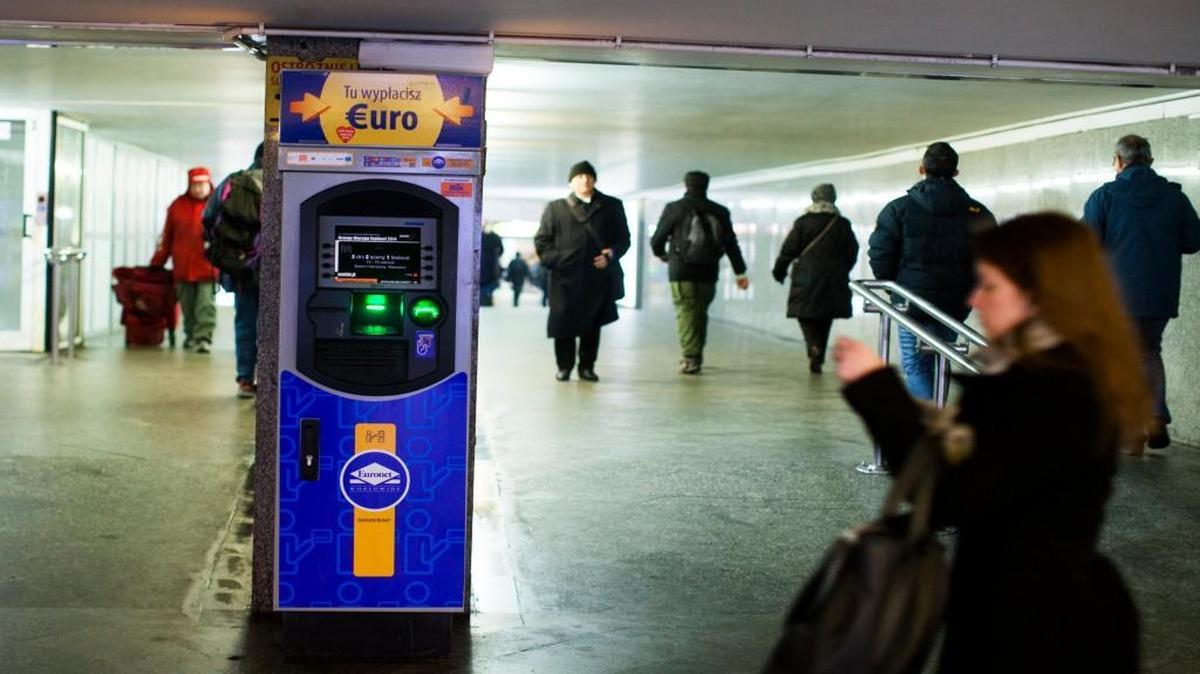 Pedestrians pass an automated teller machine operated by Euronet Worldwide in Warsaw, Poland