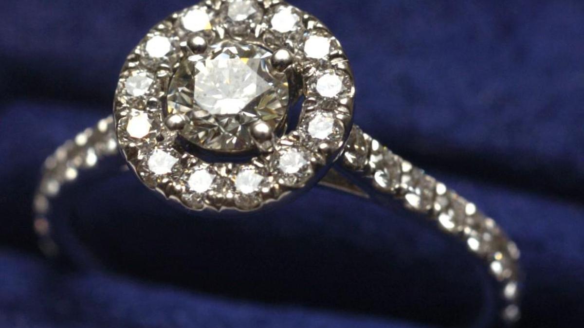 A "halo" style engagement ring with brilliant cut center diamond set in 18K white gold